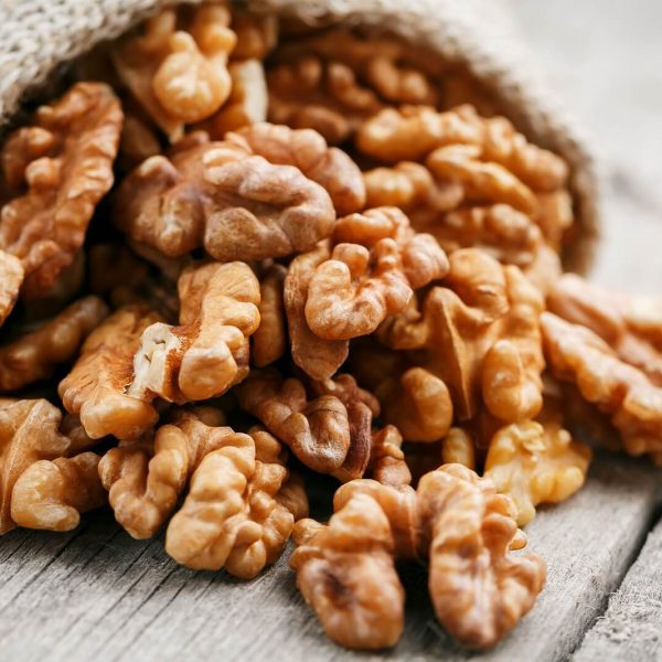 Walnuts in a burlap bag on a wooden background. Walnut macro - edible kernels of seeds. Healthy and healthy food for vegetarians